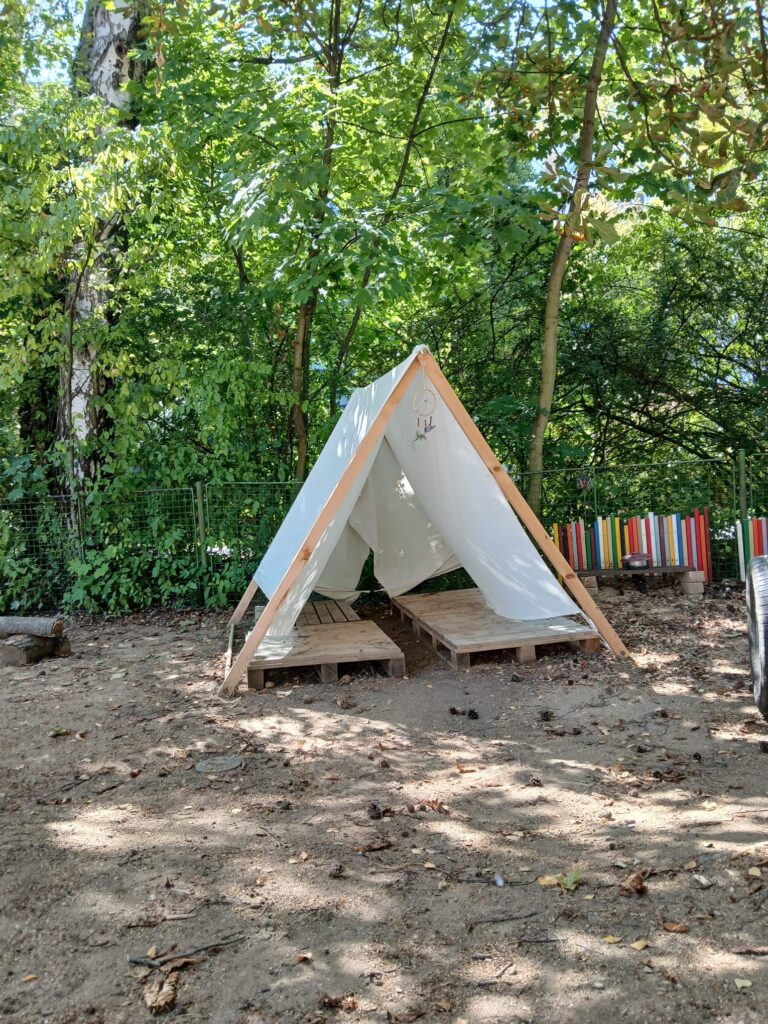 Dřevěný stan s bílou plachtou na školní zahradě