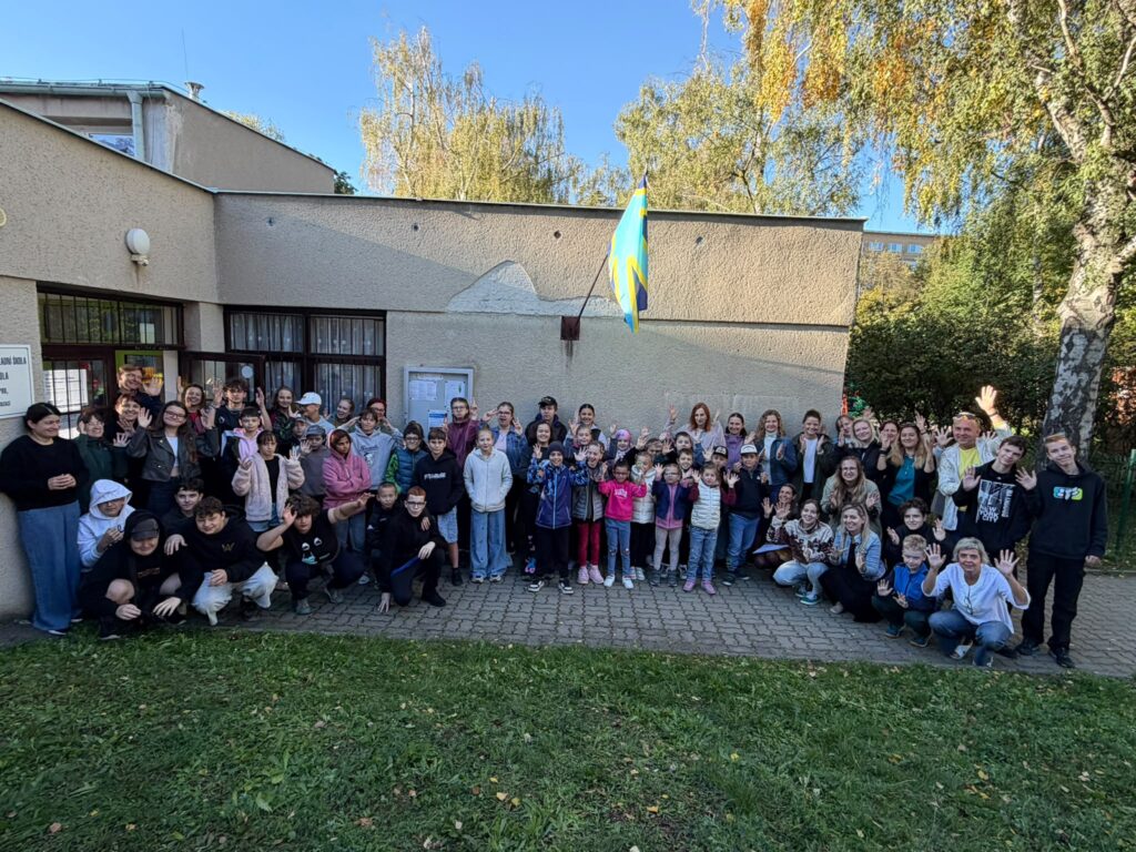 Společná fotografie žáků a pedagogů před budovou základní školy na Mezinárodní den neslyšících a znakových jazyků