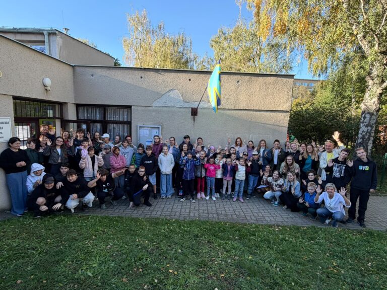 Společná fotografie žáků a pedagogů před budovou základní školy na Mezinárodní den neslyšících a znakových jazyků