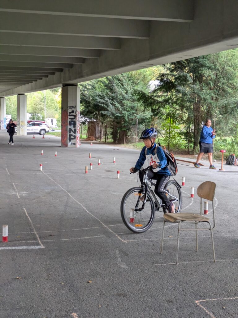 Žák projíždí na kole slalom mezi kužely při jízdě zručnosti.