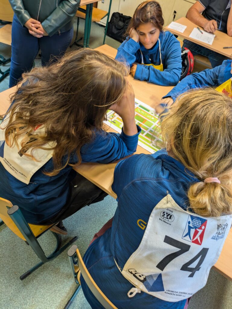 Dívky se startovními čísly pracují u lavic na úkolech z pravidel silničního provozu.